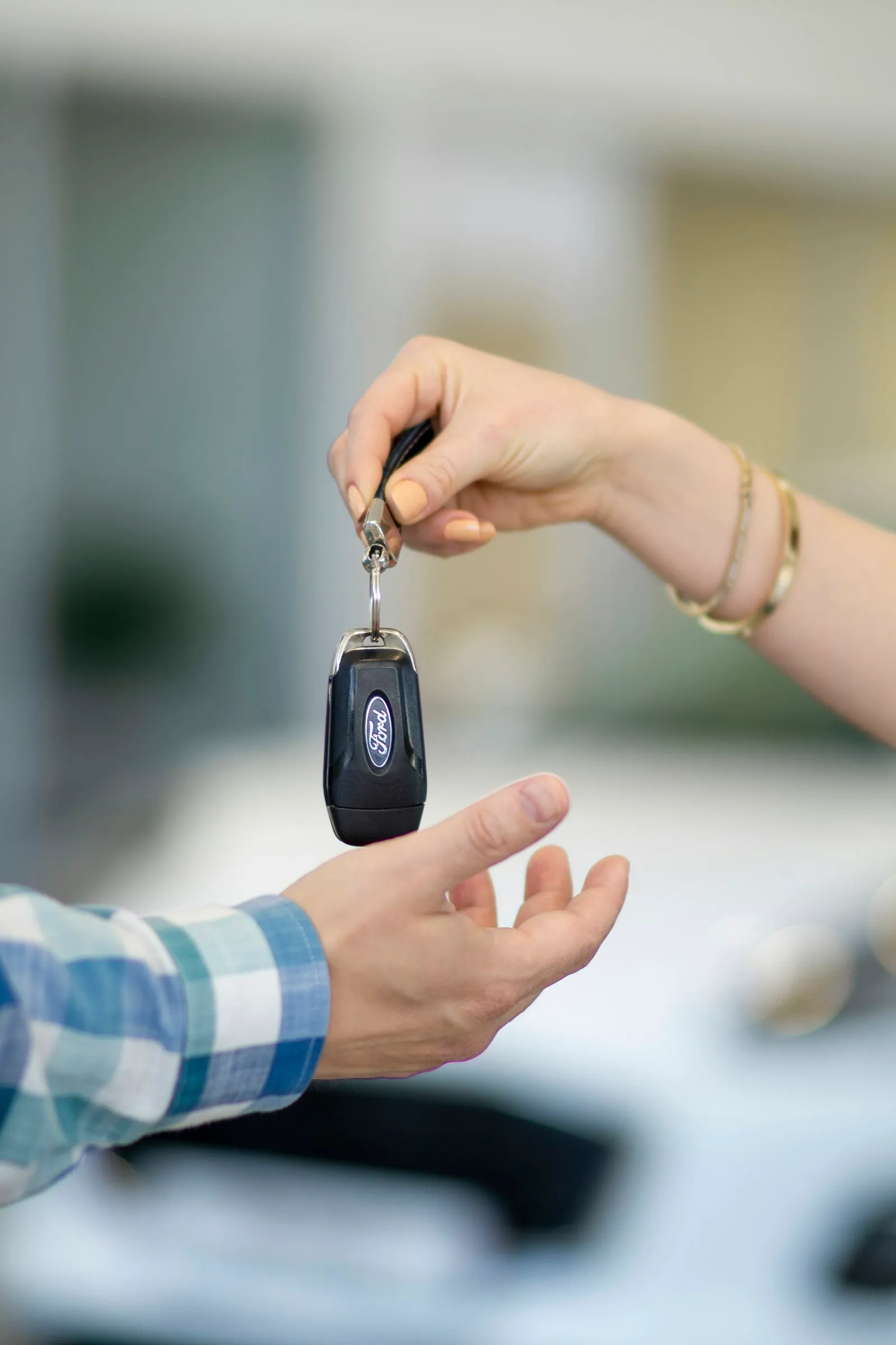 Verkäuferin übergibt einem Kunden den Fahrzeugschlüssel